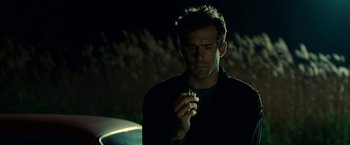 Movie still from “Green Lantern” (2011), directed by Martin Campbell – A man holding a cell phone while standing in the dark; Close Up shot, Over the shoulder angle