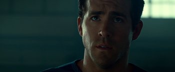 Movie still from “Green Lantern” (2011), directed by Martin Campbell – A man's face in a dark room; Close Up shot, Over the shoulder angle