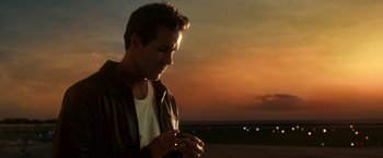 Movie still from “Green Lantern” (2011), directed by Martin Campbell – A man looking down at his cell phone at sunset; Close Up shot, Low angle