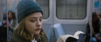Movie still from “Greta” (2018), directed by Neil Jordan – A woman sitting on a train reading a book; Close Up shot, Over the shoulder angle
