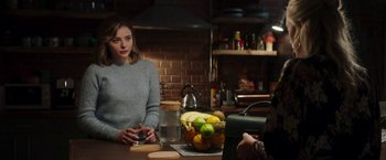 Movie still from “Greta” (2018), directed by Neil Jordan – A woman sitting at a table in front of a bowl of fruit; Medium shot, Over the shoulder angle