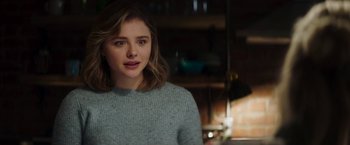 Movie still from “Greta” (2018), directed by Neil Jordan – A young woman in a blue sweater looking at the camera; Close Up shot, Over the shoulder angle