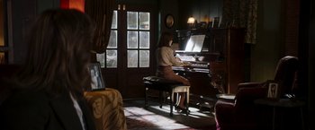 Movie still from “Greta” (2018), directed by Neil Jordan – A woman sitting at a piano in a living room; Wide shot, High angle