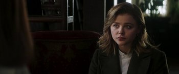 Movie still from “Greta” (2018), directed by Neil Jordan – A woman sitting on a couch in front of a window; Close Up shot, Over the shoulder angle