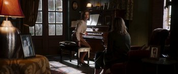 Movie still from “Greta” (2018), directed by Neil Jordan – A woman sitting at a piano in front of another woman; Wide shot, Over the shoulder angle