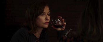 Movie still from “Greta” (2018), directed by Neil Jordan – A woman holding a glass of red wine in front of her face; Close Up shot, High angle