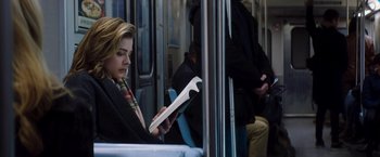 Movie still from “Greta” (2018), directed by Neil Jordan – A woman sitting on a train reading a book; Medium shot, Low angle