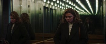 Movie still from “Greta” (2018), directed by Neil Jordan – A woman standing in front of an elevators in a building; Medium shot, Low angle