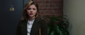 Movie still from “Greta” (2018), directed by Neil Jordan – A young woman in a green jacket looking to her left; Close Up shot, Over the shoulder angle