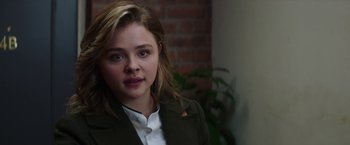 Movie still from “Greta” (2018), directed by Neil Jordan – A young woman with long blonde hair wearing a white shirt; Close Up shot, Over the shoulder angle