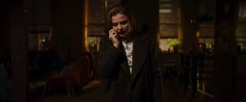 Movie still from “Greta” (2018), directed by Neil Jordan – A woman talking on a cell phone while wearing a coat; Medium shot, Low angle
