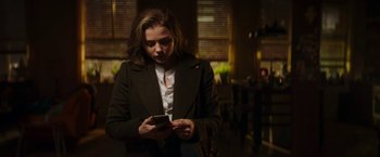 Movie still from “Greta” (2018), directed by Neil Jordan – A woman in a suit looking at her cell phone; Medium shot, Low angle