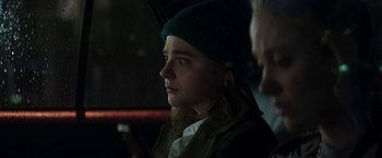Movie still from “Greta” (2018), directed by Neil Jordan – A woman sitting in the back of a car wearing a green hat; Close Up shot, Over the shoulder angle