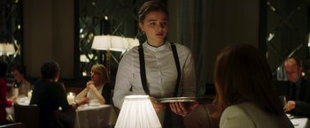 Movie still from “Greta” (2018), directed by Neil Jordan – A woman holding a silver tray in a restaurant; Medium shot, Over the shoulder angle