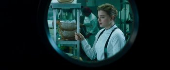 Movie still from “Greta” (2018), directed by Neil Jordan – A woman in white shirt and black tie in a kitchen; Medium shot, Low angle