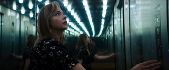 Movie still from “Greta” (2018), directed by Neil Jordan – Two women are standing next to each other in front of a mirror; Medium shot, Low angle