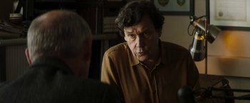 Movie still from “Greta” (2018), directed by Neil Jordan – A man in a yellow shirt is talking to another man; Close Up shot, Over the shoulder angle