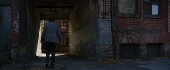 Movie still from “Greta” (2018), directed by Neil Jordan – A person walking down a street near a brick wall; Wide shot, Low angle