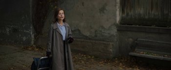 Movie still from “Greta” (2018), directed by Neil Jordan – A woman walking down the street wearing a trench coat; Medium shot, Over the shoulder angle