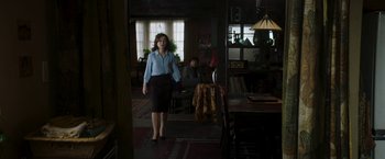 Movie still from “Greta” (2018), directed by Neil Jordan – A woman in a blue shirt and black skirt standing in a room; Wide shot, Over the shoulder angle