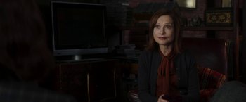 Movie still from “Greta” (2018), directed by Neil Jordan – A woman sitting in front of a television in a dark room; Close Up shot, Over the shoulder angle