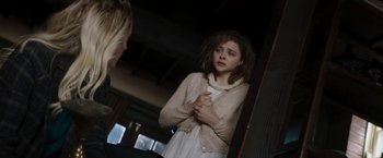 Movie still from “Greta” (2018), directed by Neil Jordan – A young girl in a white dress looking in a mirror; Medium shot, Over the shoulder angle