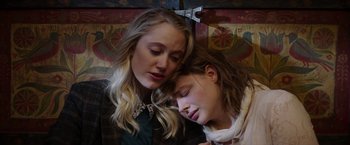 Movie still from “Greta” (2018), directed by Neil Jordan – Two young women snuggling on the side of a train; Close Up shot, High angle
