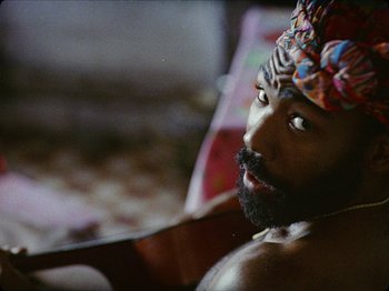 Movie still from “Guava Island” (2019), directed by Hiro Murai – A man with a beard wearing a turban; Close Up shot, Overhead angle