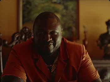 Movie still from “Guava Island” (2019), directed by Hiro Murai – A person wearing an orange jacket; Close Up shot, Low angle