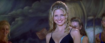 Movie still from “I Know What You Did Last Summer” (1997), directed by Jim Gillespie – A woman in a black dress smiling for the camera; Close Up shot, Over the shoulder angle