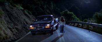 Movie still from “I Know What You Did Last Summer” (1997), directed by Jim Gillespie – A woman walking down a street next to a truck; Wide shot, High angle
