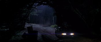 Movie still from “I Know What You Did Last Summer” (1997), directed by Jim Gillespie – A car driving down a dirt road in the dark; Extreme Wide shot, High angle