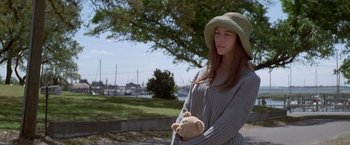 Movie still from “I Know What You Did Last Summer” (1997), directed by Jim Gillespie – A woman holding a teddy bear while standing in a park; Medium shot, Over the shoulder angle