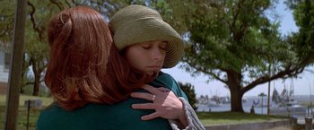 Movie still from “I Know What You Did Last Summer” (1997), directed by Jim Gillespie – A woman in a hat is hugging another woman in a green sweater; Close Up shot, Over the shoulder angle