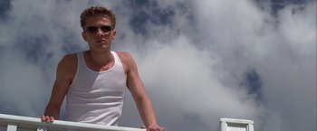 Movie still from “I Know What You Did Last Summer” (1997), directed by Jim Gillespie – A man in a white tank top is standing on a boat in the water; Medium shot, Low angle