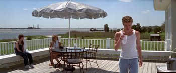 Movie still from “I Know What You Did Last Summer” (1997), directed by Jim Gillespie – Two women sitting at an outdoor table drinking water; Wide shot, Over the shoulder angle