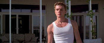 Movie still from “I Know What You Did Last Summer” (1997), directed by Jim Gillespie – A man in a white tank top standing in front of a house; Medium shot, Low angle