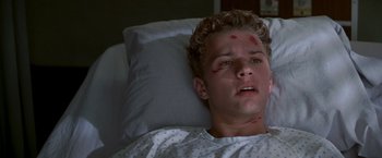 Movie still from “I Know What You Did Last Summer” (1997), directed by Jim Gillespie – A young man laying in a hospital bed with a bandage on his face; Close Up shot, Low angle