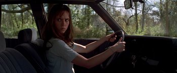 Movie still from “I Know What You Did Last Summer” (1997), directed by Jim Gillespie – A woman driving a car in the woods; Close Up shot, Low angle