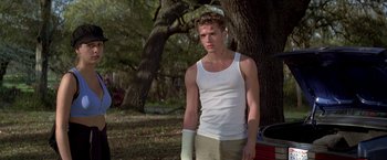 Movie still from “I Know What You Did Last Summer” (1997), directed by Jim Gillespie – A man in a white tank top standing next to a tree; Medium shot, Low angle