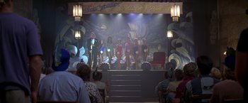 Movie still from “I Know What You Did Last Summer” (1997), directed by Jim Gillespie – A group of people standing on a stage in front of a mural; Wide shot, Low angle