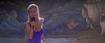 Movie still from “I Know What You Did Last Summer” (1997), directed by Jim Gillespie – A woman in a blue dress is holding a microphone; Medium shot, Low angle