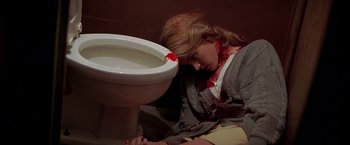 Movie still from “I Know What You Did Last Summer” (1997), directed by Jim Gillespie – A woman with blood all over her face is laying on the floor next to a white toilet; Close Up shot, High angle