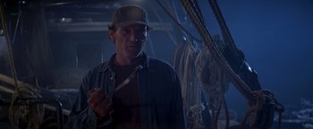 Movie still from “I Know What You Did Last Summer” (1997), directed by Jim Gillespie – A man holding a knife standing in front of ropes on a boat; Medium shot, Low angle