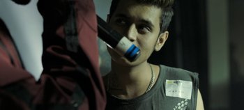 Movie still from “Gully Boy” (2019), directed by Zoya Akhtar – A young man is drinking a bottle of wine; Close Up shot, Over the shoulder angle