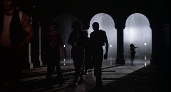 Movie still from “Hair” (1979), directed by Milos Forman – A group of people walking on a sidewalk at night; Wide shot, Low angle