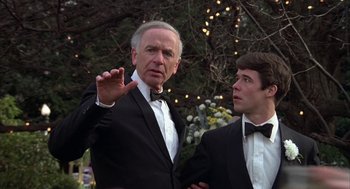 Movie still from “Hair” (1979), directed by Milos Forman – A man in a suit and tie next to another man in a suit and bow tie; Close Up shot, Over the shoulder angle