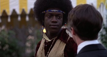 Movie still from “Hair” (1979), directed by Milos Forman – A man with a large afro wearing a headband; Close Up shot, Over the shoulder angle