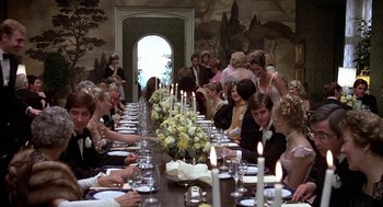 Movie still from “Hair” (1979), directed by Milos Forman – A group of people sitting around a long table; Wide shot, High angle