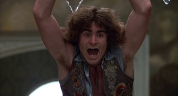 Movie still from “Hair” (1979), directed by Milos Forman – A man with a hairy shirt is holding his arms up; Close Up shot, Low angle